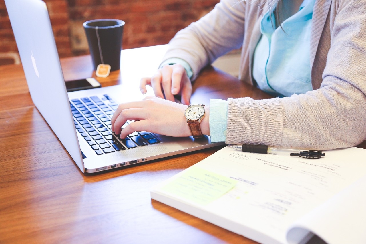 Person working on their laptop at a desk with a cup of coffee.
