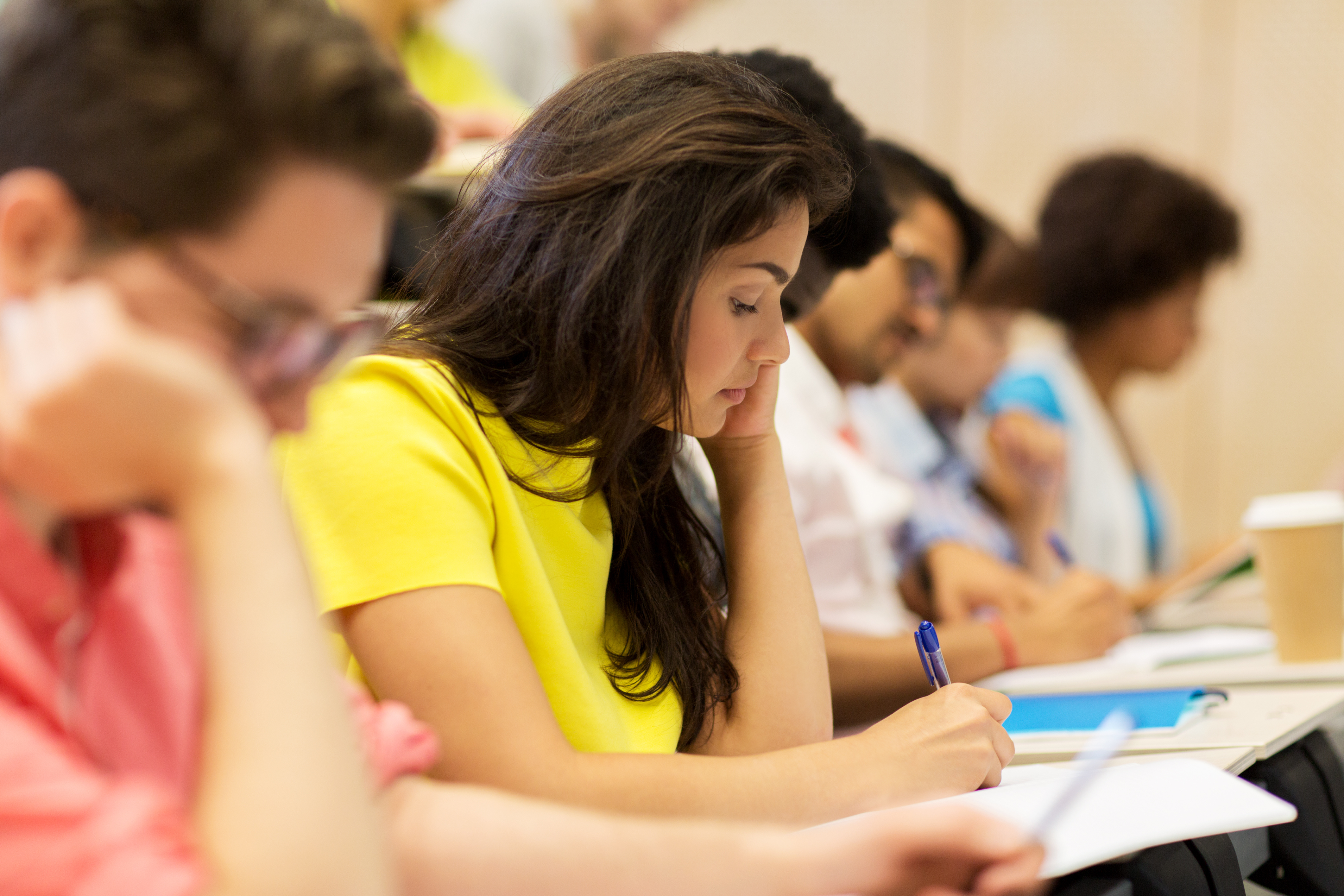 Row of students taking a test while sitting at desks.